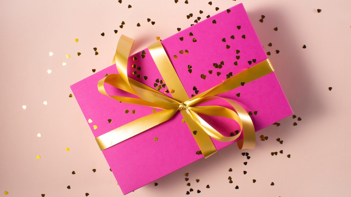 A pink, wrapped presented with a gold ribbon