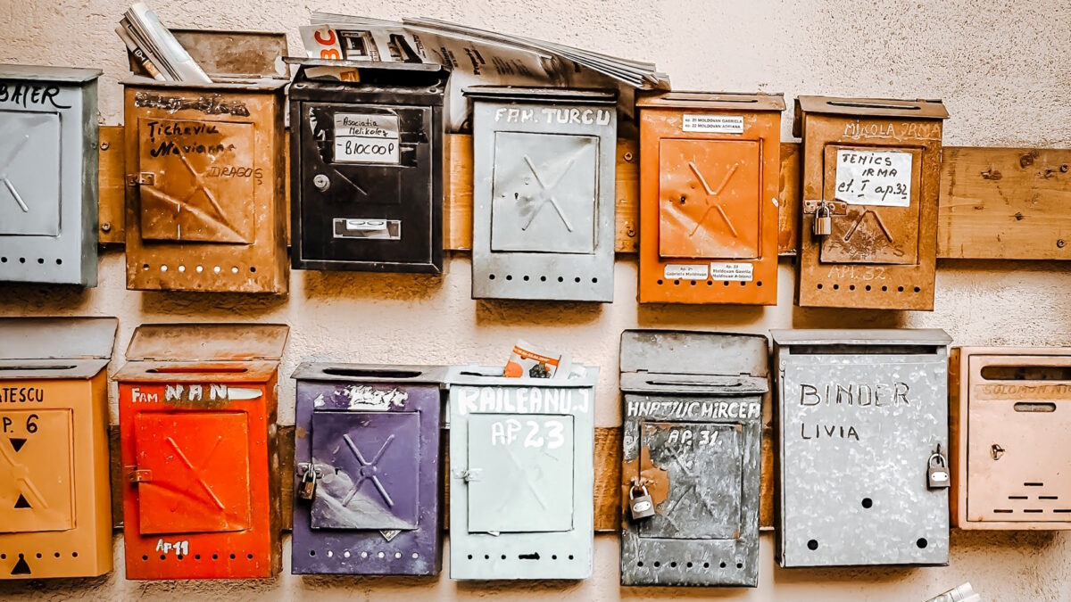 A diverse range of mailboxes stuck to a wall